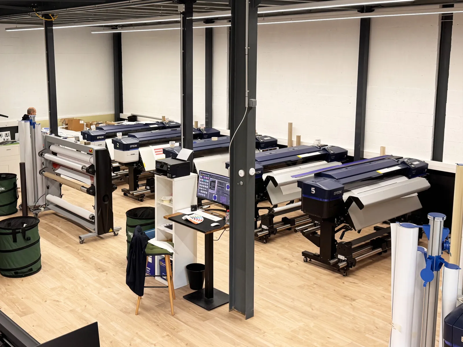 Atelier de production SORA : rangée d'imprimantes grand format et laminateur dans un grand espace de travail