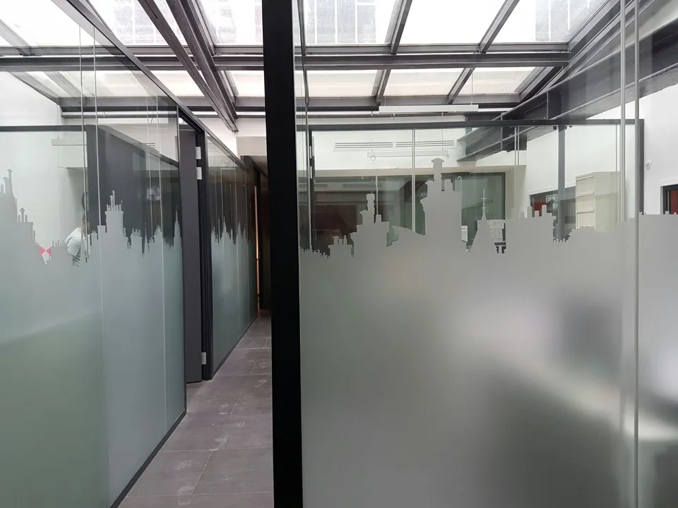 Couloir de bureaux avec cloisons vitrées habillées d'une skyline en film dépoli